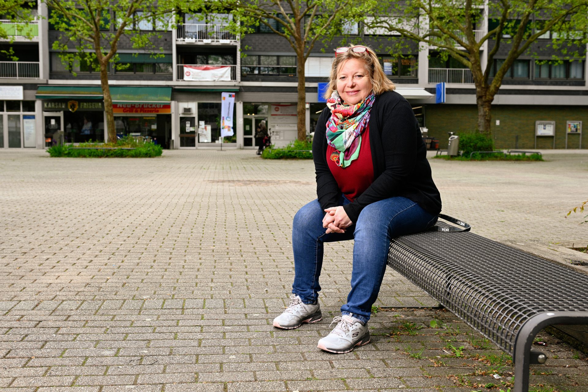 Eine Frau sitzt auf einer Bank vor einem Gebäude.